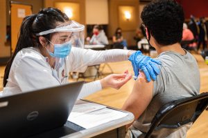 Maica Ho administers COVID-19 vaccine to a patient at a vaccination clinic